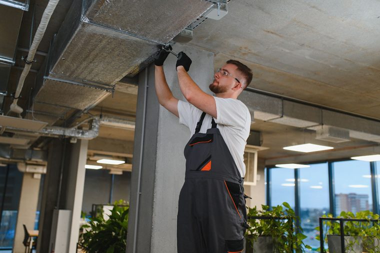 Professional technician working on hvac ductwork installation and maintenance, ensuring optimal air quality in a contemporary office environment